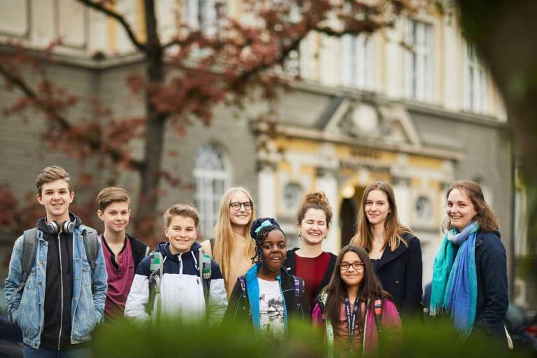 Eine Gruppe von Schüler*innen unterschiedlichen Alters vor dem Eingang des BRG Fadingerstraße